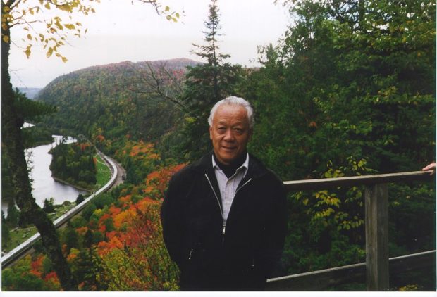 Jack Kobayashi dehors avec les arbres et une rivière en bas dans une vallée