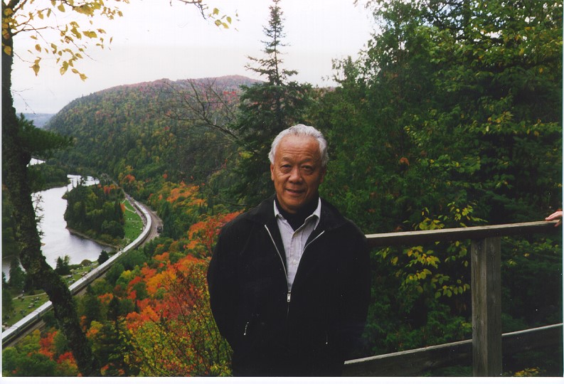 Jack Kobayashi dehors avec les arbres et une rivière en bas dans une vallée