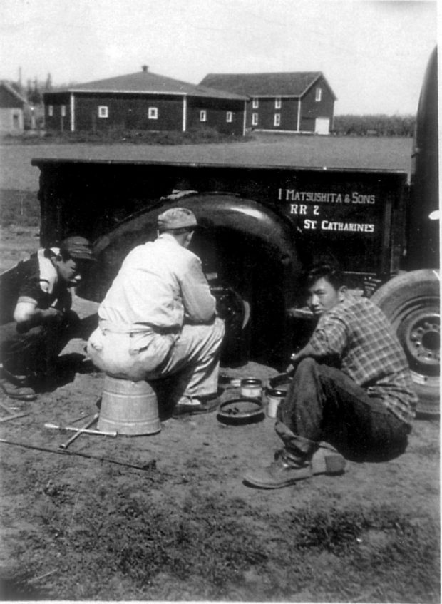 Trois hommes à côté du volant d'un camion réparant le pneu