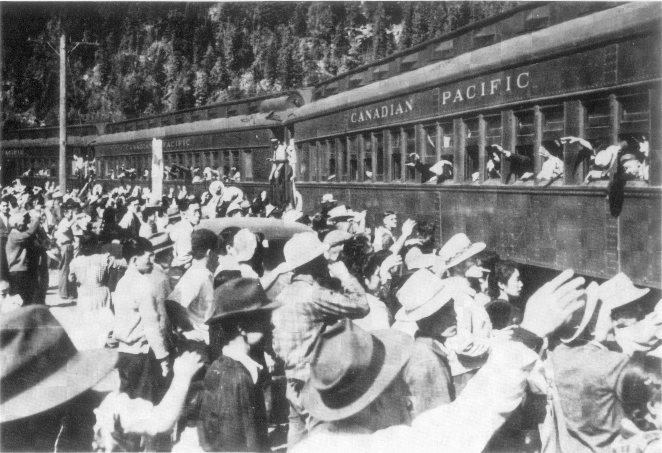 Un grand groupe de personnes s'est réuni le long d'un train en agitant au revoir