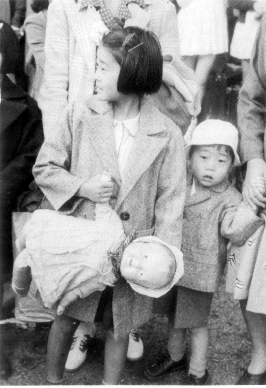 Jeune fille tenant une poupée et la main de son jeune frère attendant d'être exilée