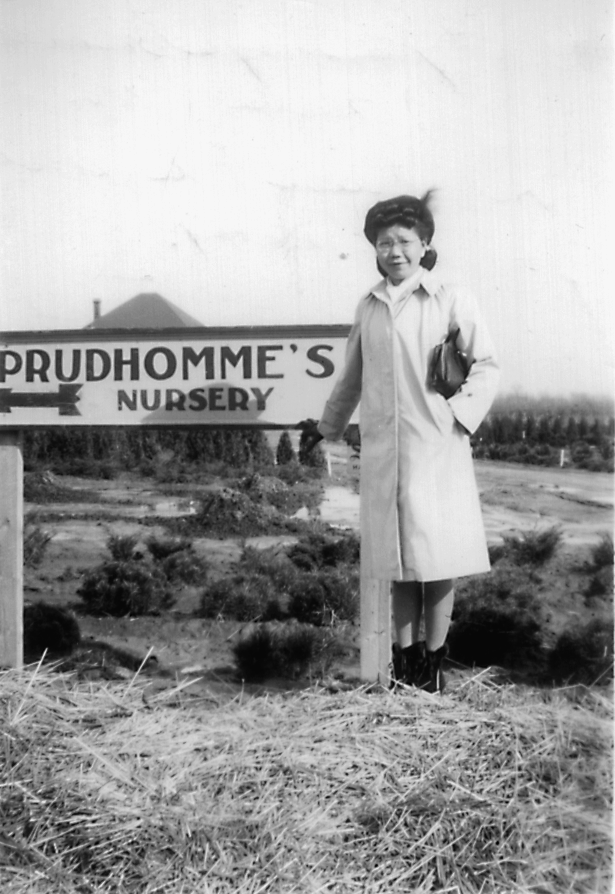 Femme debout devant une pancarte indiquant Prudhomme's Nursery