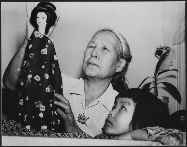 Une femme âgée tenant une poupée habillée à la mode japonaise et une jeune fille observant