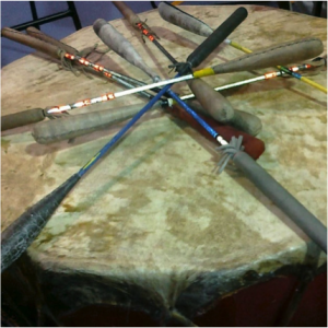 rand tambour utilisé dans un pow wow avec  plusieurs bâtons laissés sur le dessus. Photo en couleur. 