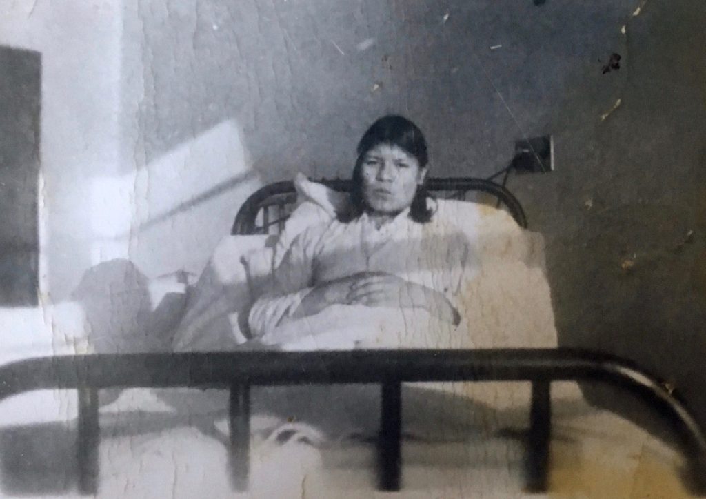 Une femme anicinabe assise dans son lit au sanatorium de St-Jean de Macamic. Photo en noir et blanc. 
