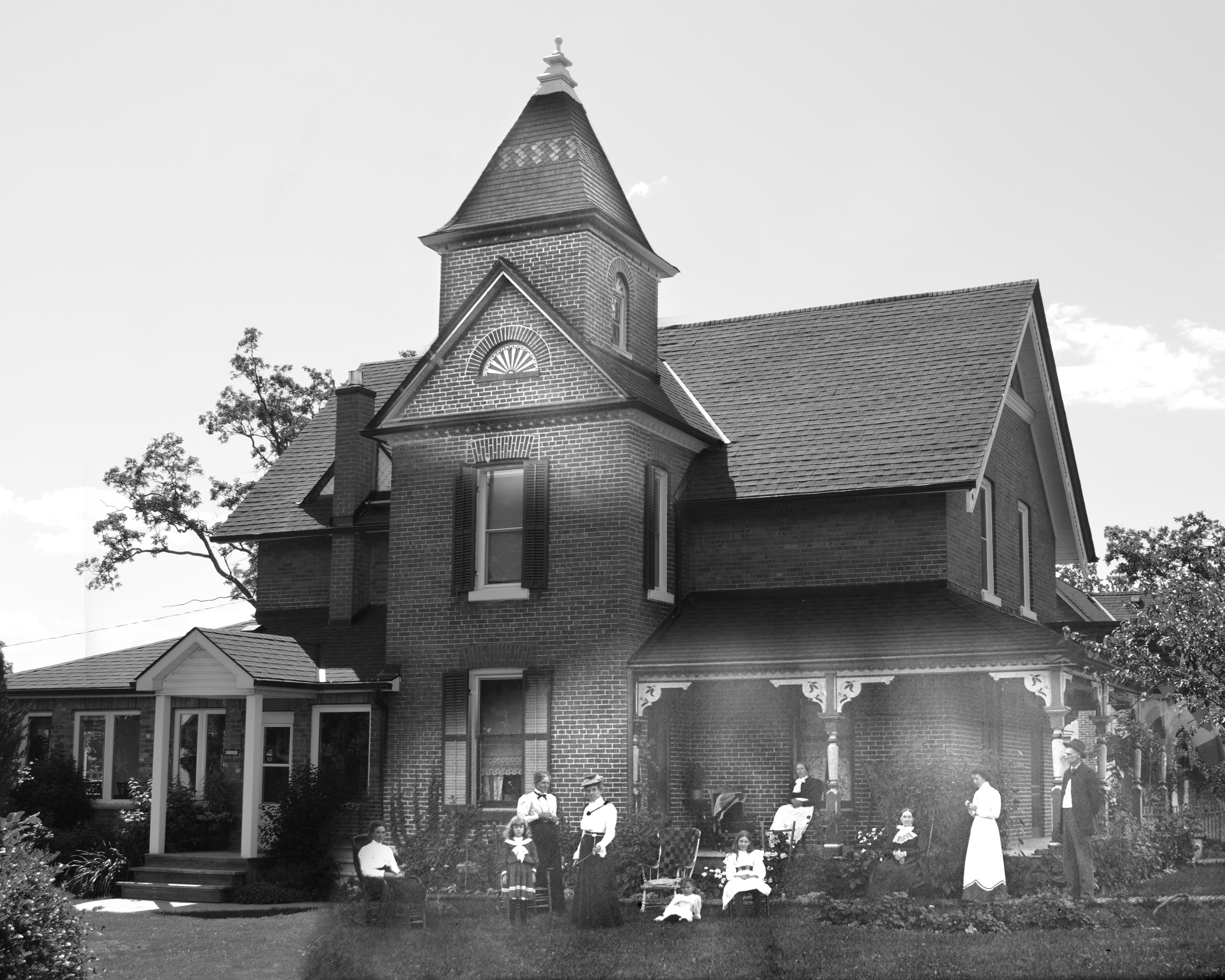 Des photos noir et blanc fusionnées d’une maison en briques avec un une tour proéminente; la photo historique montre un groupe de personnes rassemblées sur la pelouse. 