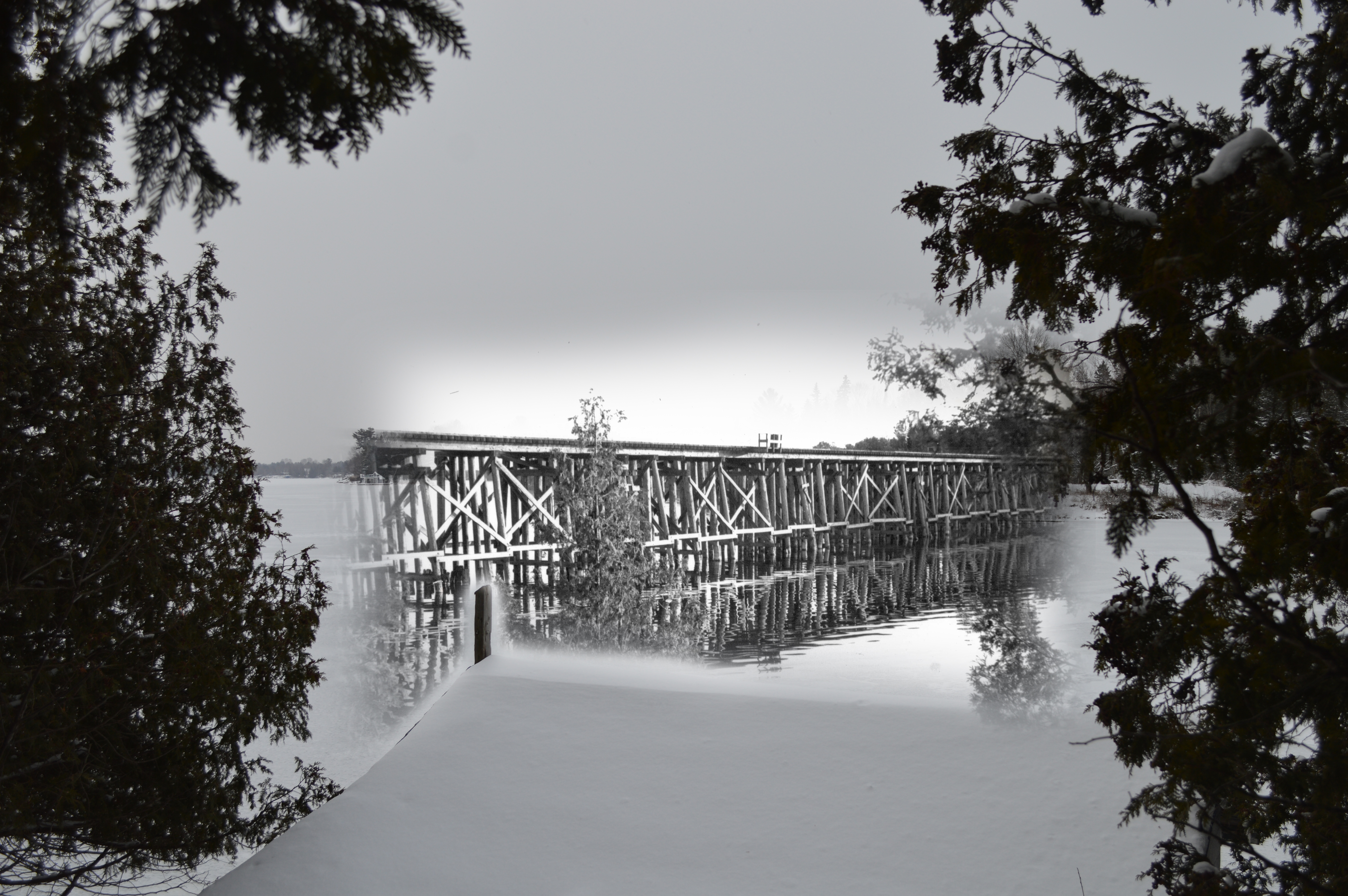 Une photo en noir et blanc d'un pont ferroviaire en bois se fond dans une image contemporaine — dans laquelle le pont n'existe plus.