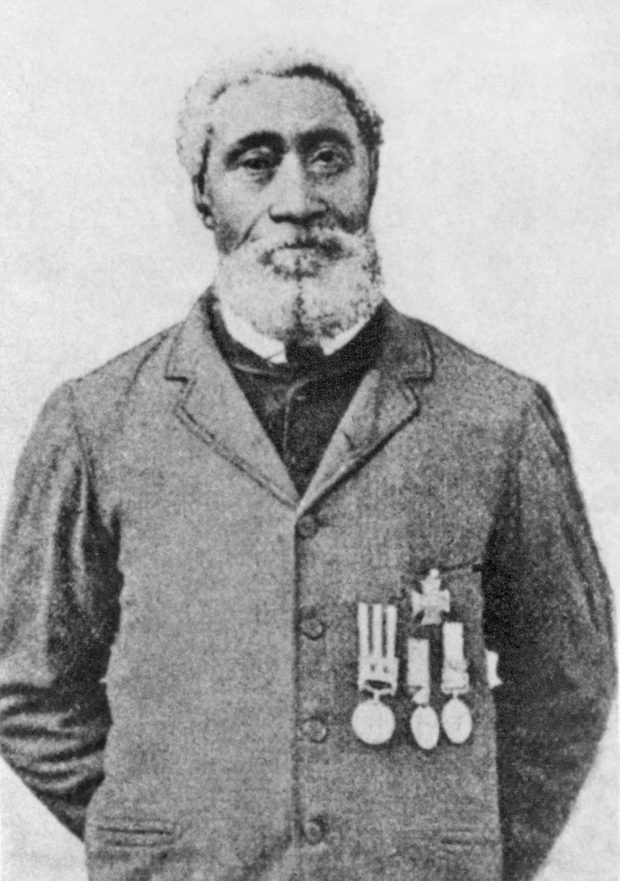 Photo en noir et blanc d’un soldat noir portant ses médailles sur un veston civil.