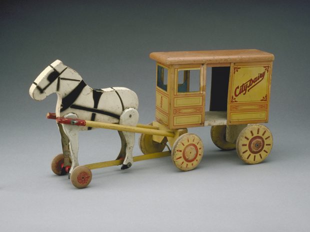 Jouet en bois, avec un cheval tirant une voiture de laitier, peinte en jaune terne, orange et rouge.