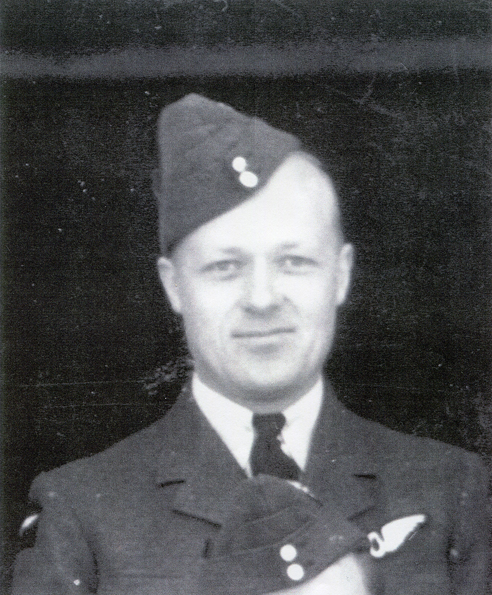 Photo granuleuse en noir et blanc d’un aviateur canadien en uniforme qui sourit pour l’appareil photo.