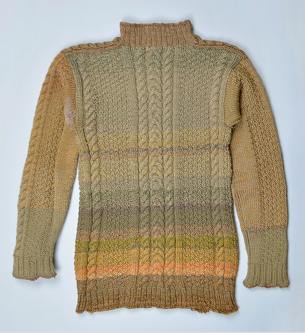 Chandail de tricot torsadé en laine de couleurs terreuses, surtout du vert mousse.