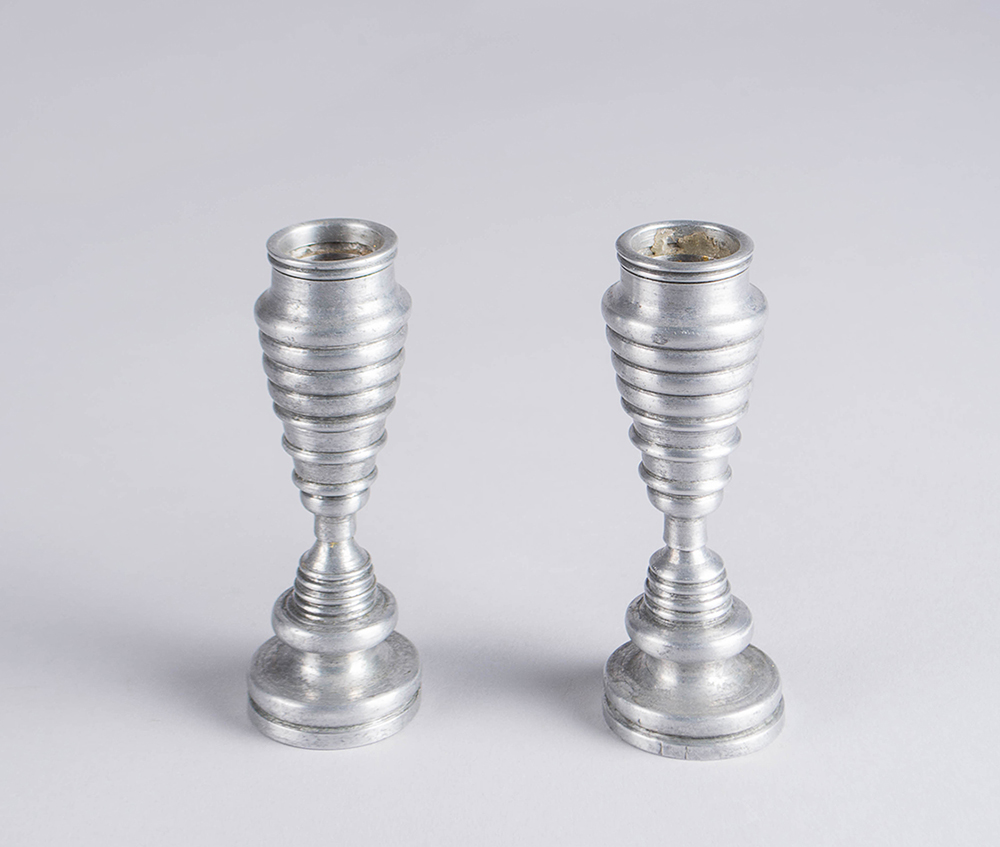 Petits chandeliers en aluminium présentant une série de bourrelets arrondis devenant progressivement plus petits puis plus grands.