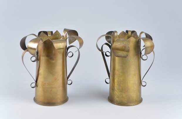 Deux vases de laiton avec pétales recourbés à la partie supérieure.  Les poignées sont faites de lamelles de laiton enroulées en spirales.