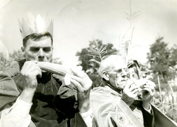 Photographie en noir et blanc de deux hommes vêtus d'une robe royale qui dégustent des épis de maïs : Norman Morrow, roi du maïs en 1950 est à gauche, et Sam Stock, roi du maïs en 1949 est à droite.