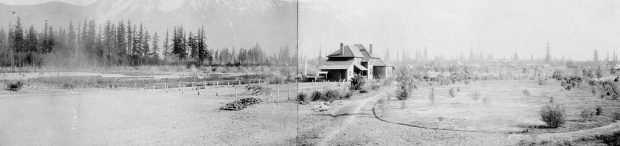 Photo en noir et blanc d'une maison dans un champ, avec des montagnes en arrière-plan.