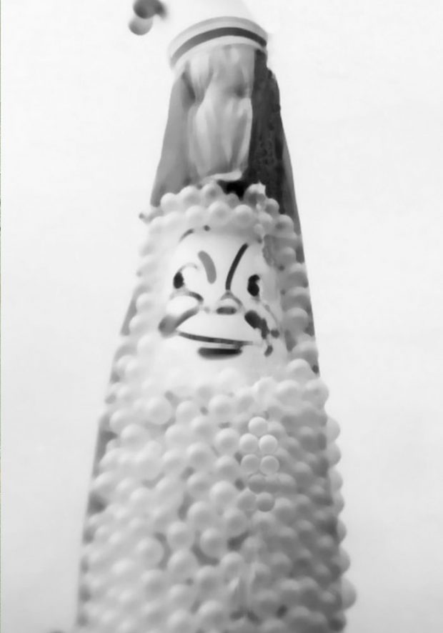Photo en noir et blanc de la mascotte de l’Agassiz Fall Fair and Corn Festival. Elle a un visage peint et est composée de ballons.