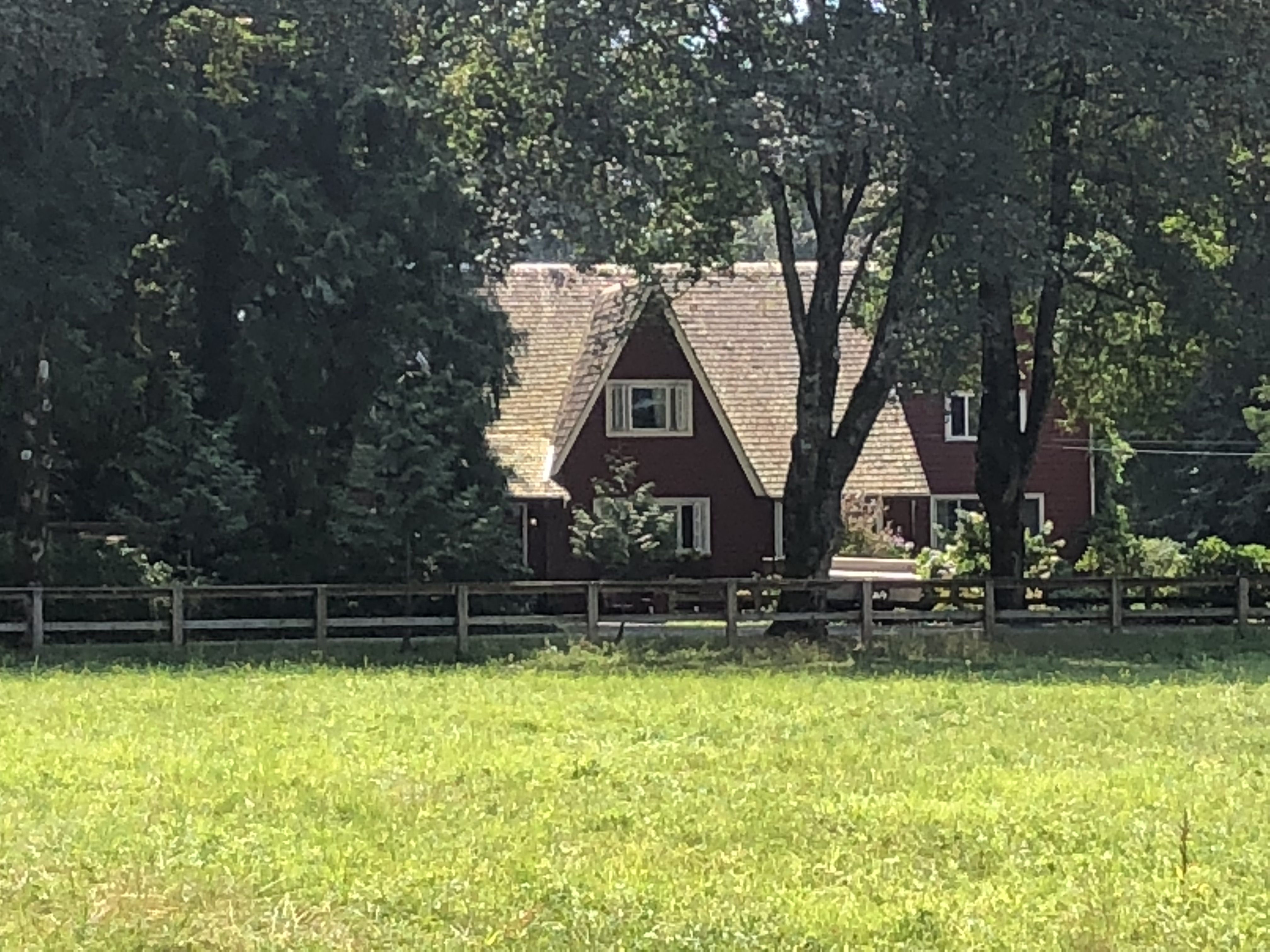 Photo en couleur d'une maison de ferme avec un champ devant.