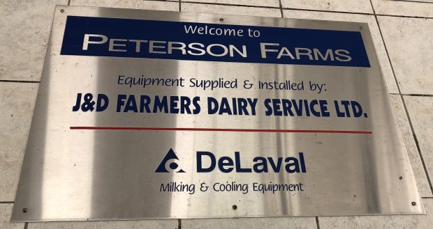Photo en couleur d'un panneau en acier inoxydable, sur lequel il est écrit « Welcome to Peterson Farms ».