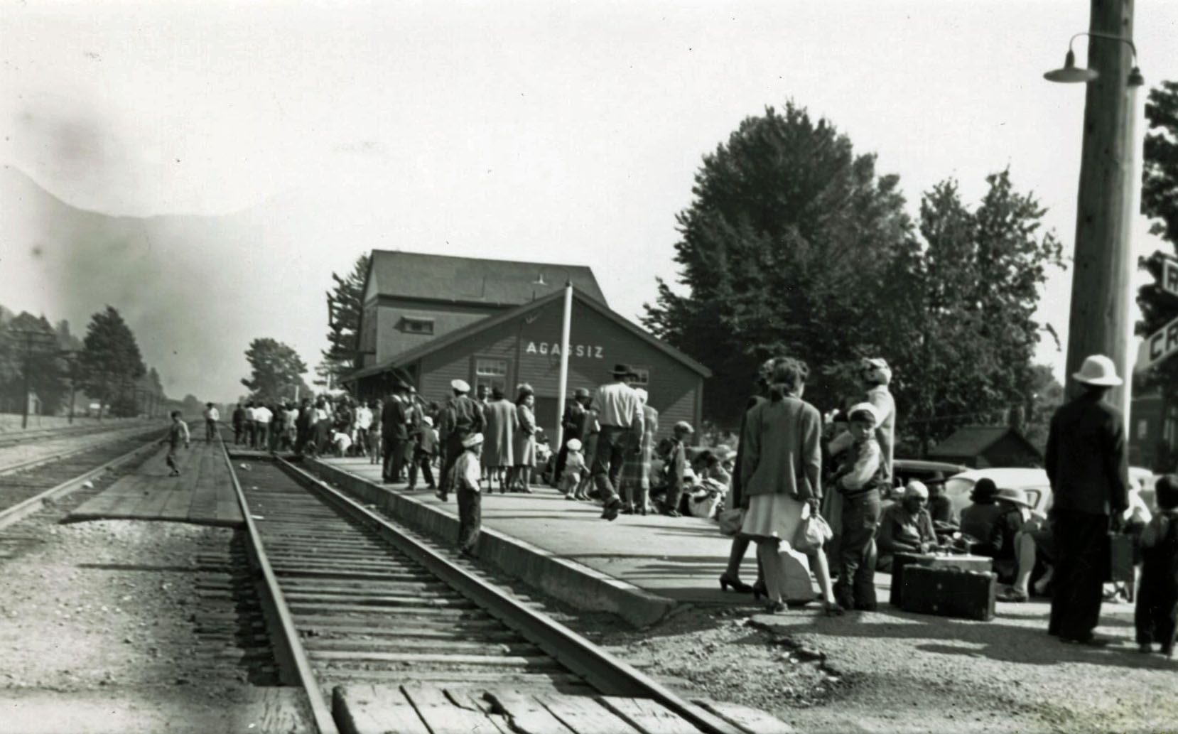 Photo en noir et blanc d'une foule de personnes sur le quai de la gare d'Agassiz.