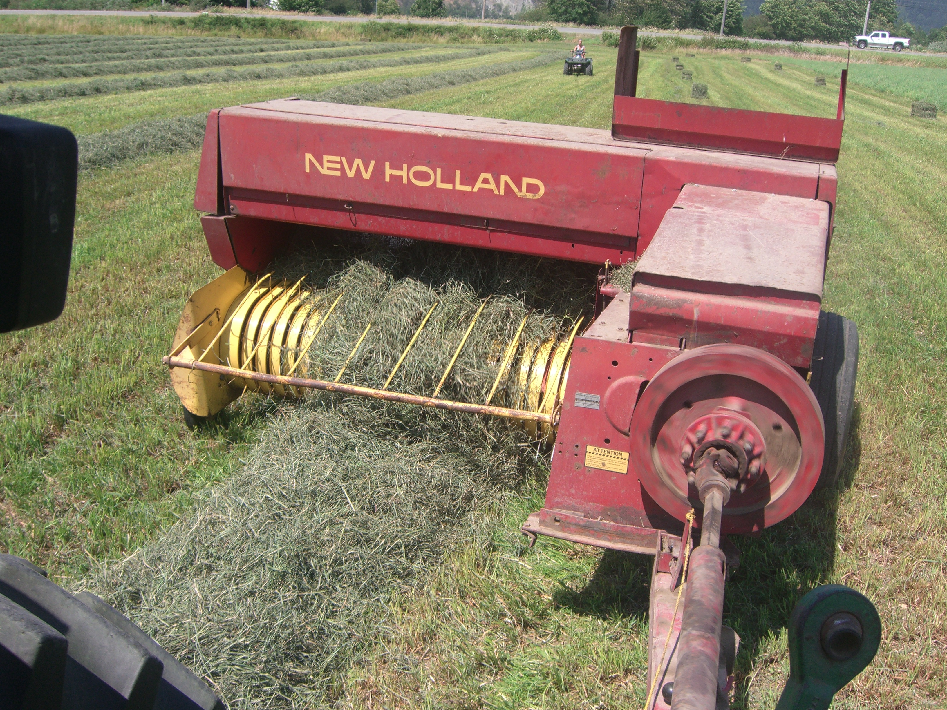 Photo en couleur d'un tracteur New Holland qui presse le foin en balles.