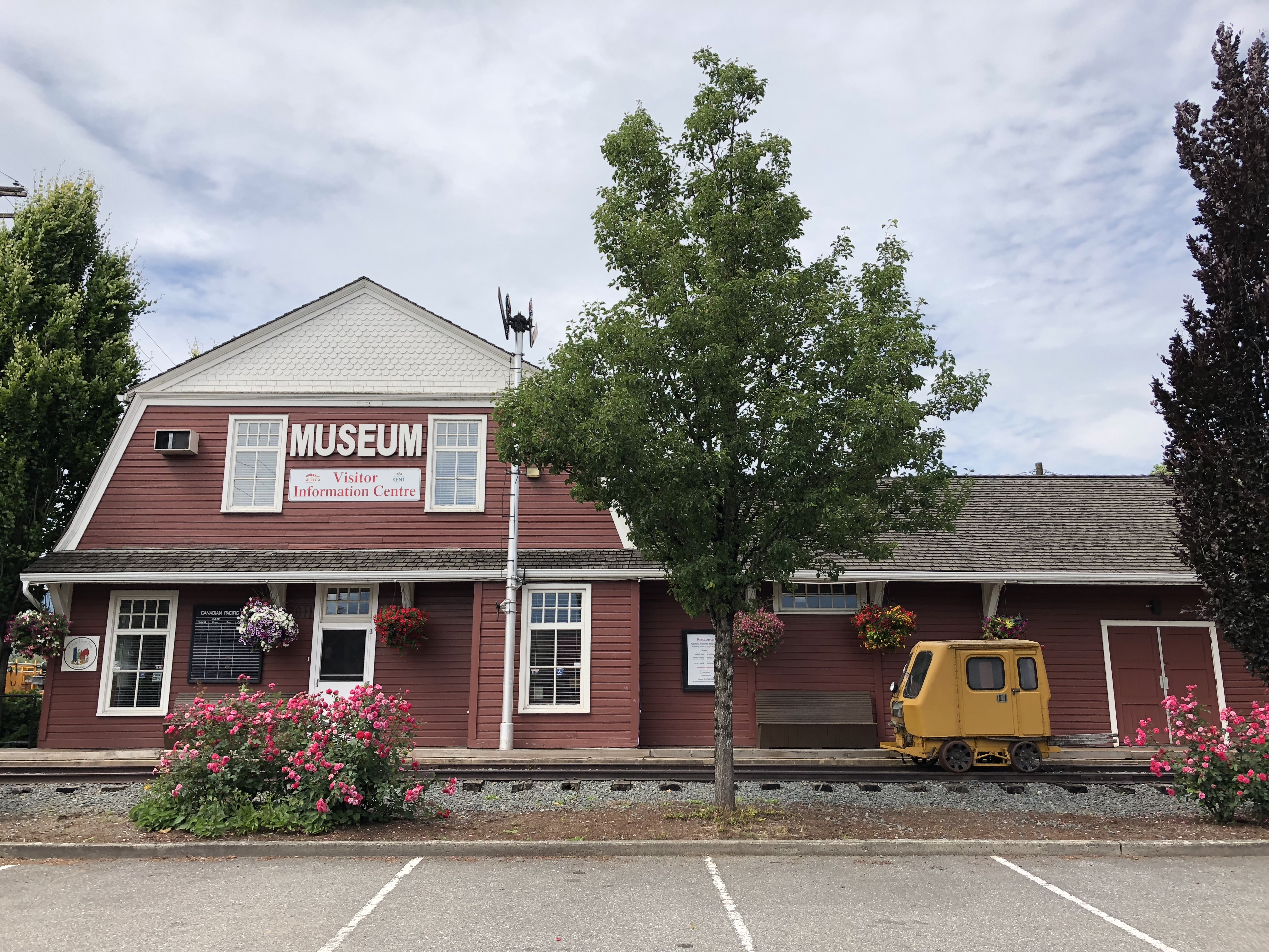 Photo en couleur d'une gare ferroviaire historique en forme de grange rouge et blanche, aujourd'hui l'Agassiz-Harrison Museum and Visitor Information Center.