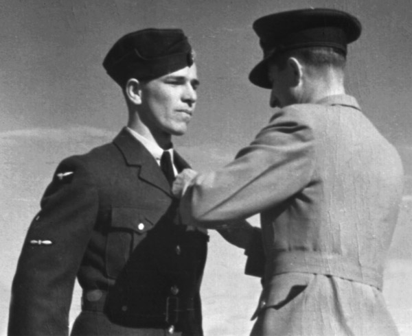 Photo en noir et blanc de deux hommes en uniforme militaire, l’un accrochant un insigne sur la poitrine de l’autre.