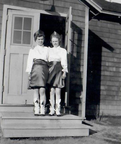 Two women in costumes in front of building
