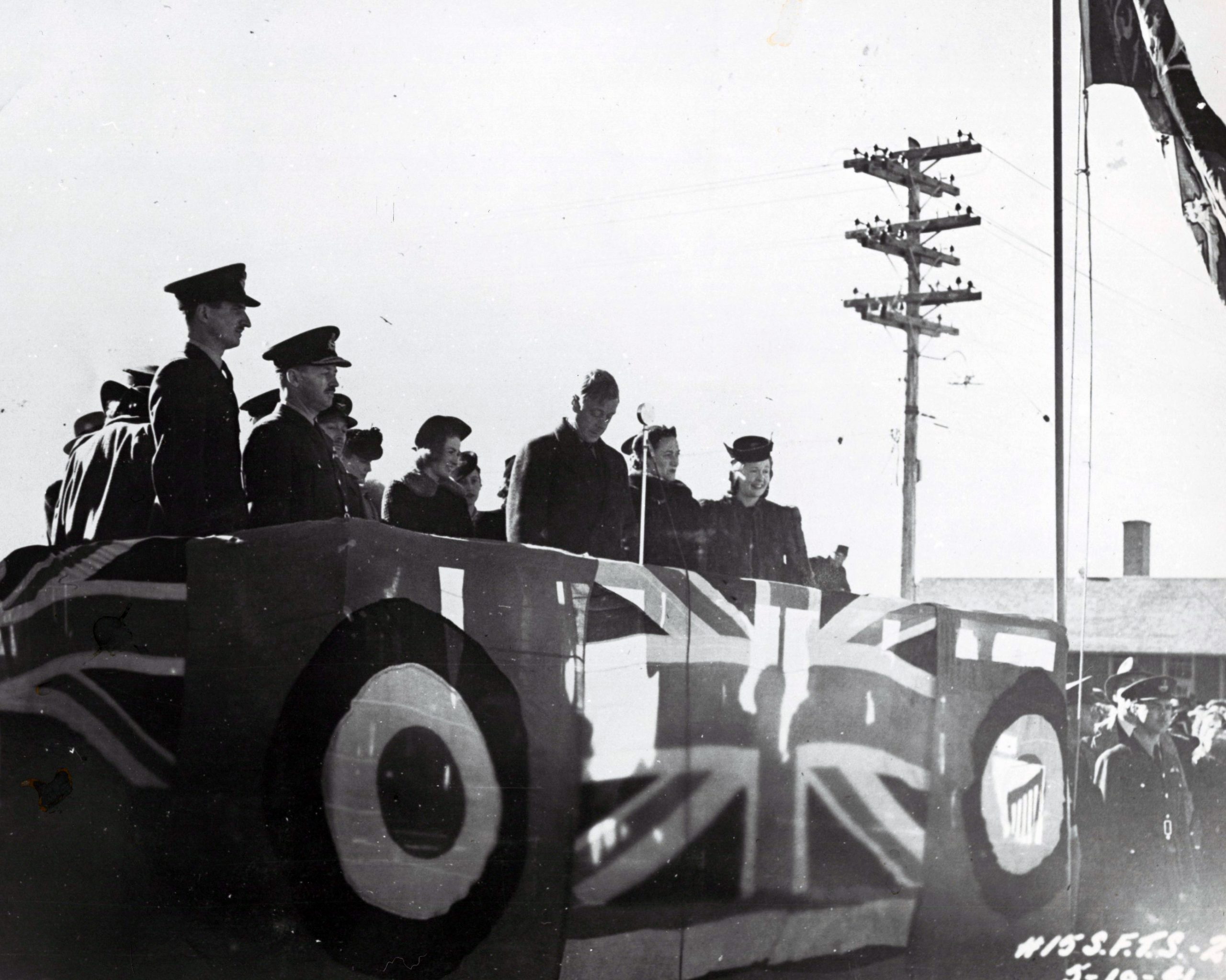 7 hommes et 4 femmes sur une plateforme couverte de drapeaux