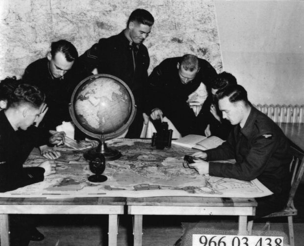 7 aviateurs regardant des cartes sur une table