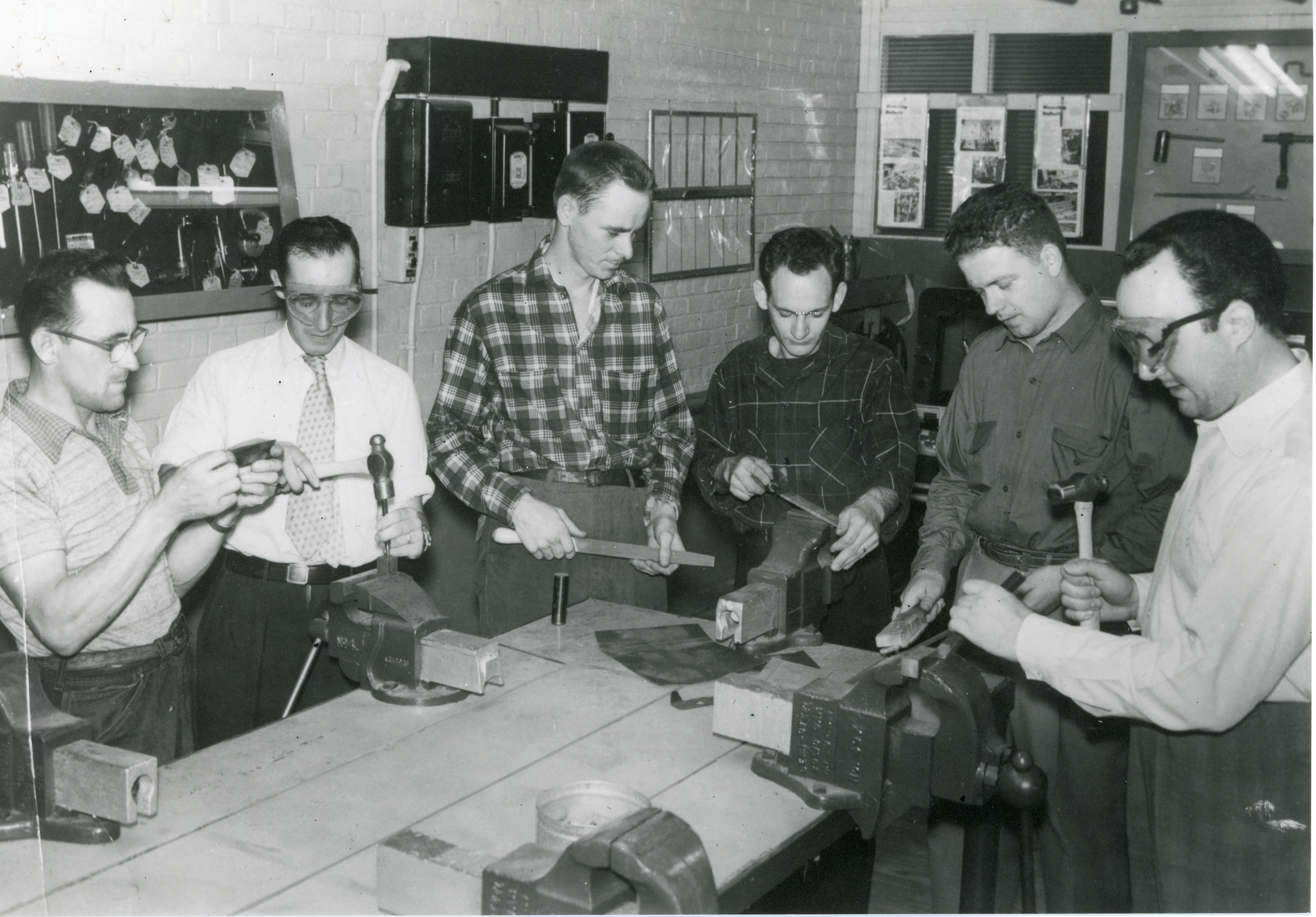 Six hommes travaillent sur un établi