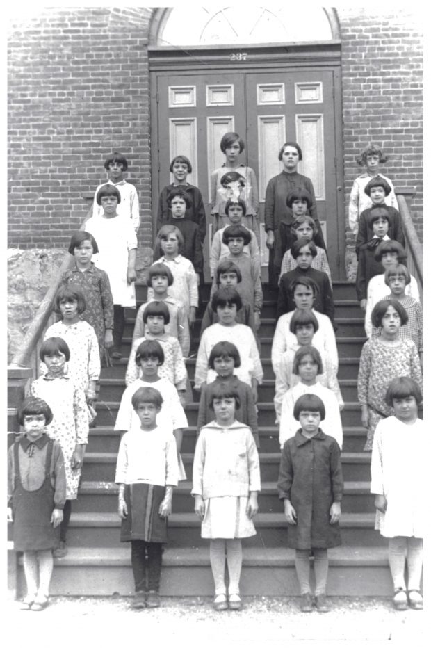 Trente-six écolières posant dans les escaliers à l'avant de la Crèche.