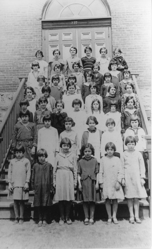 Quarante-deux écolières posent en sept rangées dans les escaliers devant la Crèche.