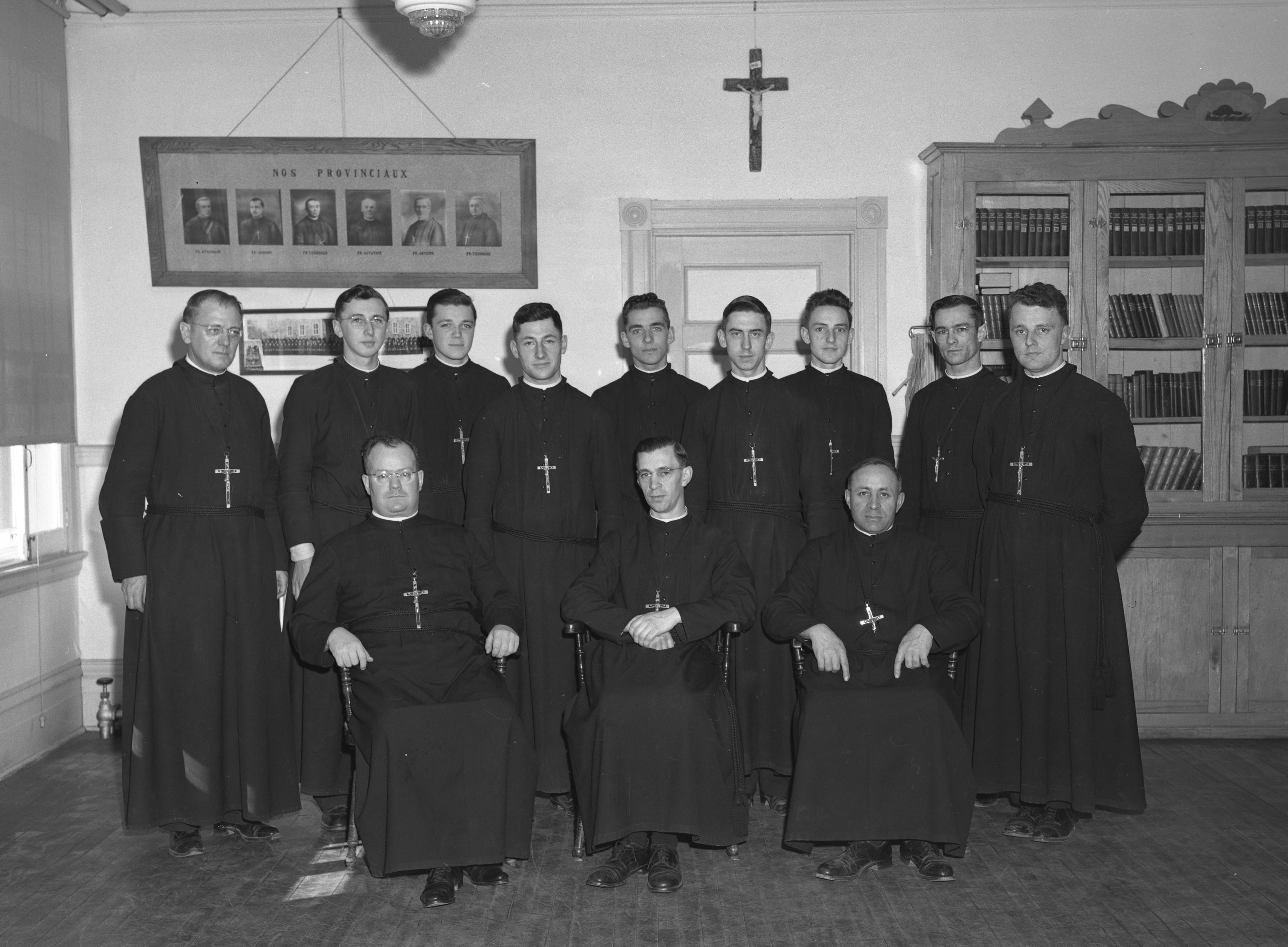 Douze frères dans leurs longs habits noirs posent en deux rangées. 