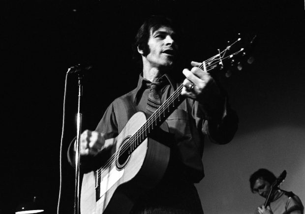 Photo noir et blanc de Claude Gauthier en spectacle tenant sa guitare.