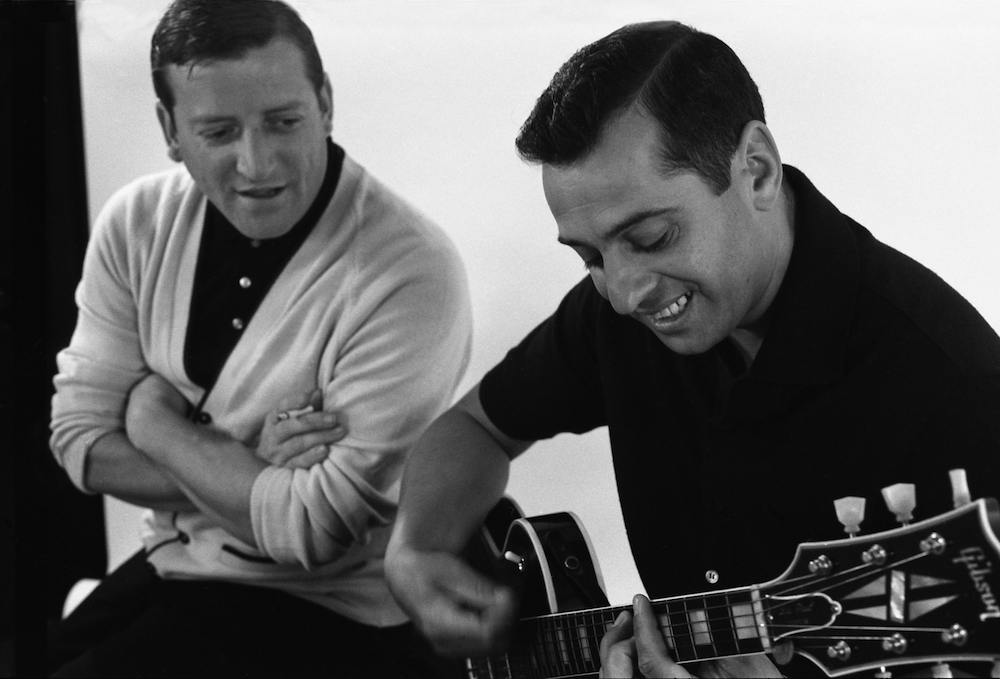 Photo noir et blanc des Jérolas. Jérôme Lemay à la guitare est écouté par Jean Lapointe.