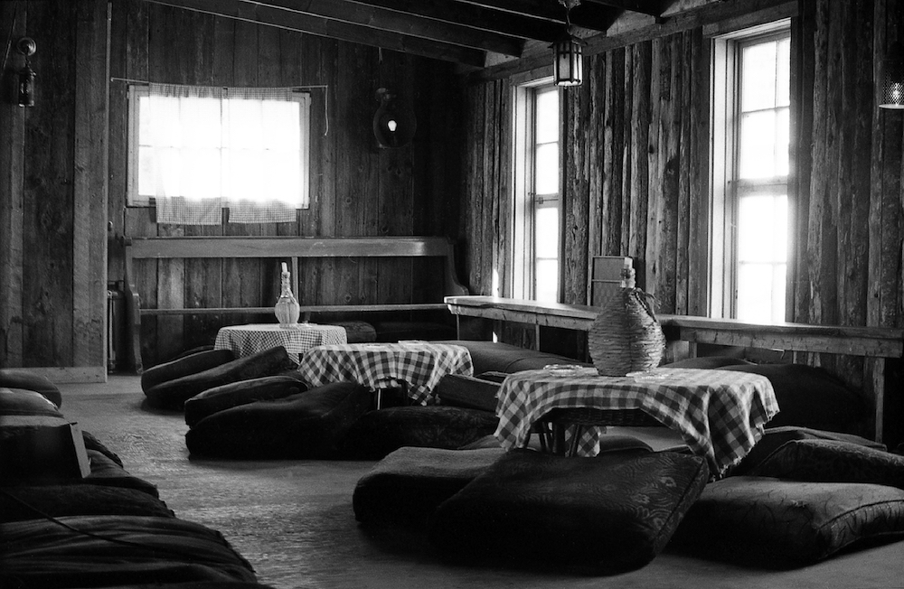 Une des deux mezzanines de la Butte avec ses tables basses couvertes de nappes à carreaux et chacune d’une chandelle plantée dans une bouteille de Chianti et ses coussins.