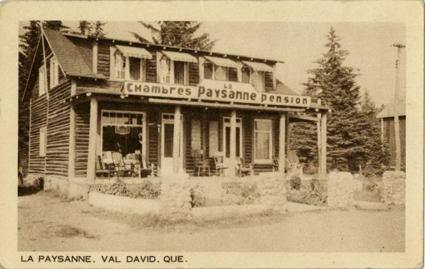 Ancienne carte postale montrant la façade de l’auberge La Paysanne à Val-David. Sur l’enseigne de la façade on peut lire La Paysanne, chambres et pensions.