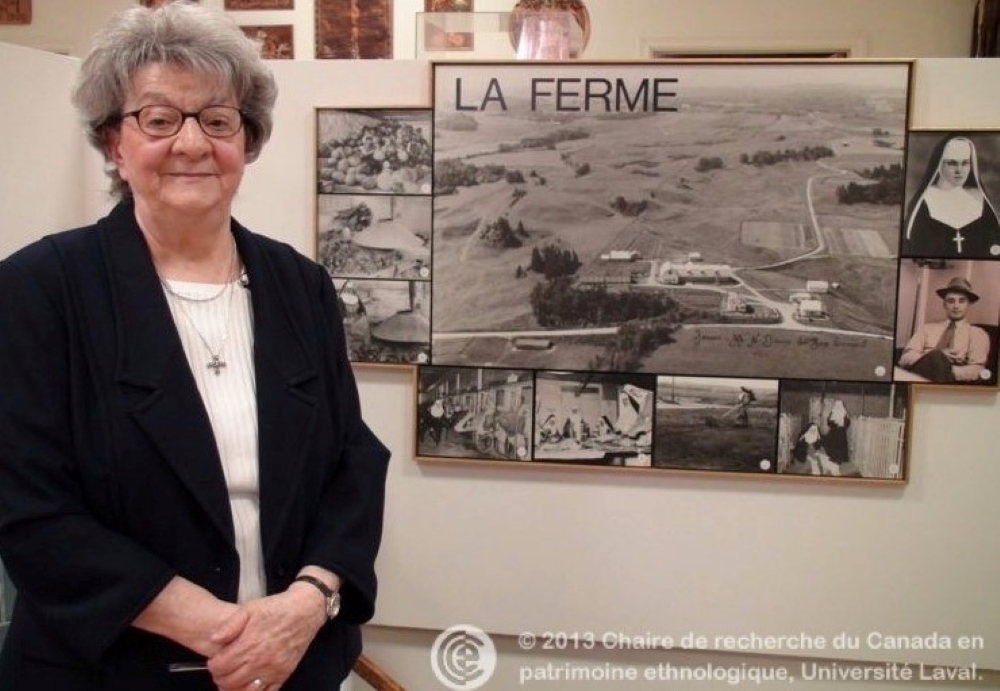 Une femme debout devant les photographies de la ferme.