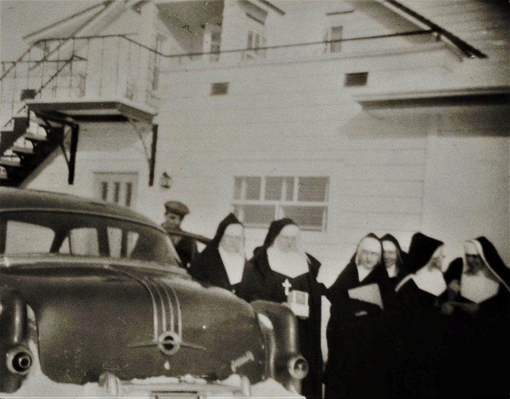 Un groupe de religieuses devant une voiture.
