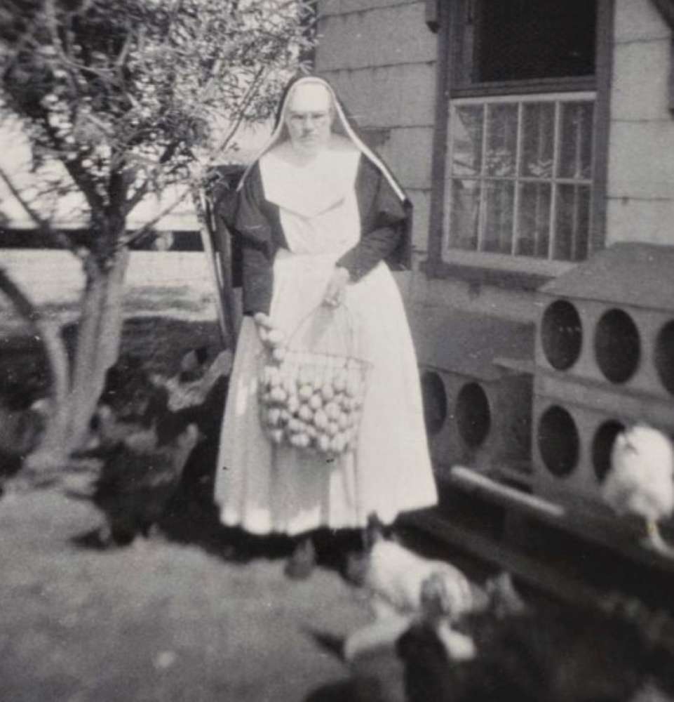 Photo en noir et blanc d’une sœur avec un gros panier en fer rempli d’œufs. 