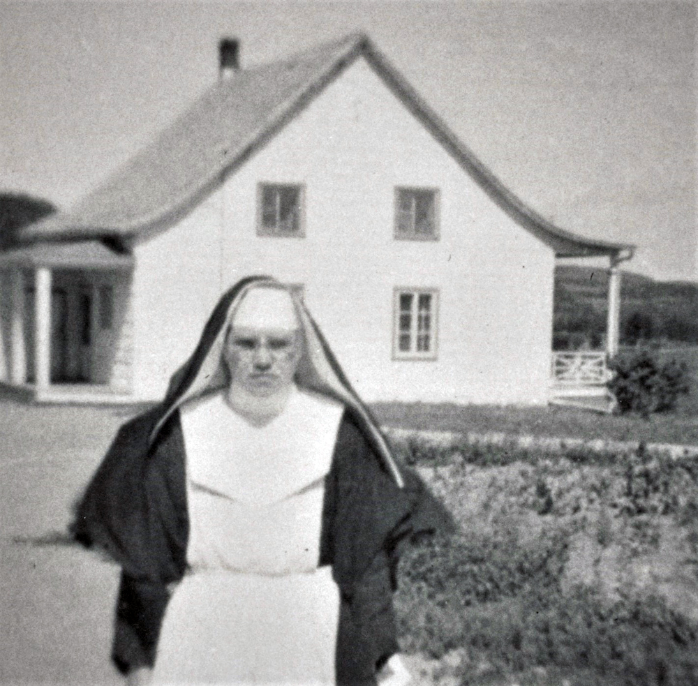 Photo en noir et blanc d’une sœur devant une maison.