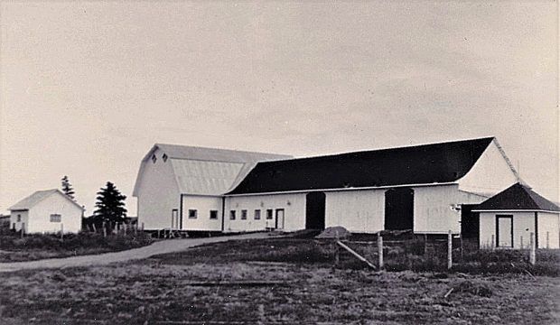Photo en noir et blanc d’un bâtiment rectangulaire surmonté d’un toit à deux versants droits.