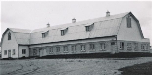 Photo grisâtre d’un bâtiment à toit brisé.  