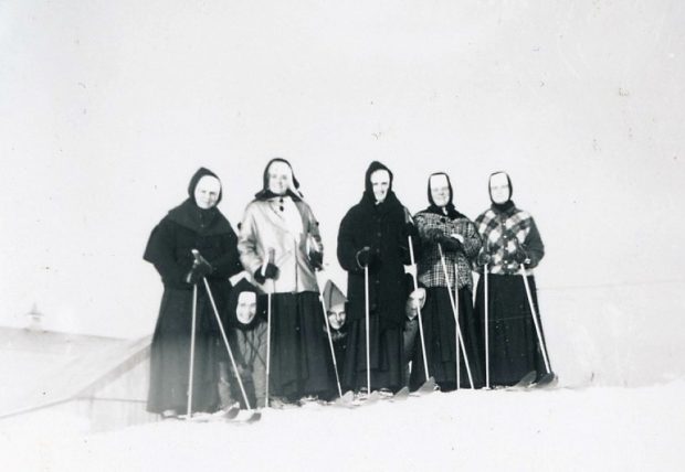 Photo en noir et blanc de cinq femmes à ski et trois femmes à genoux dans la neige. Elles portent un voile et des habits d’hiver.