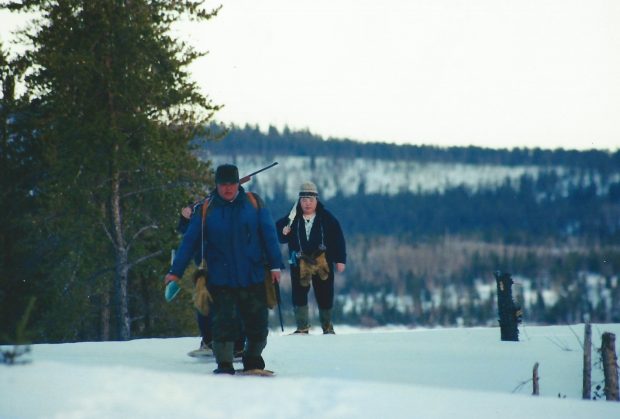 Trois personnes marchant sur des collines enneigées en hiver.