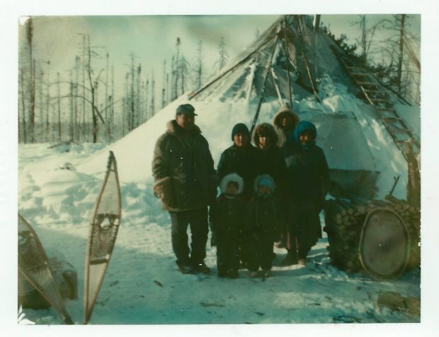 Sept personnes se tenant à côté d’un tipi enneigé.