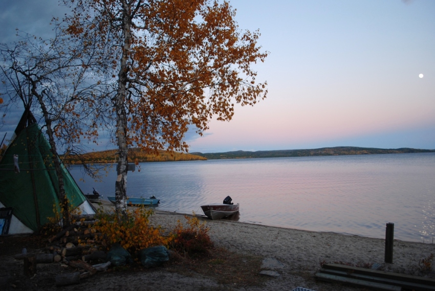 Tente, bouleau et deux bateaux à moteur au bord du lac, au coucher du soleil.
