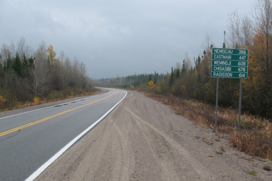 Panneau vert sur le bord de la route pavée avec ligne jaune.