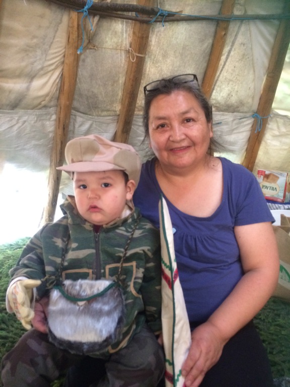 Un petit garçon assis avec sa grand-mère dans un tipi traditionnel