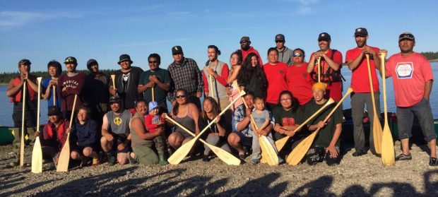 Groupe d’hommes et de femmes souriants tenant des pagaies de canot